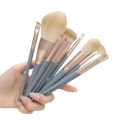 Set of eight professional synthetic makeup brushes with soft beige bristles and gray handles with rose gold ferrules