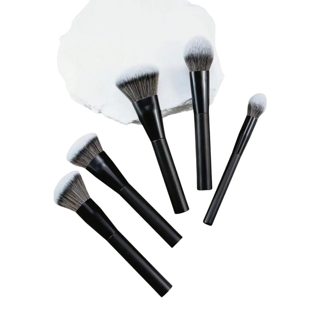 Set of five professional makeup brushes with black handles and soft gradient gray to white bristles on neutral surface