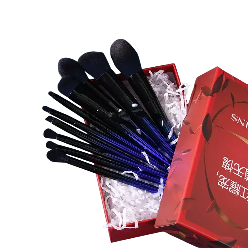 Makeup brush set with soft black and blue bristles nestled in a red gift box lined with white crinkle paper