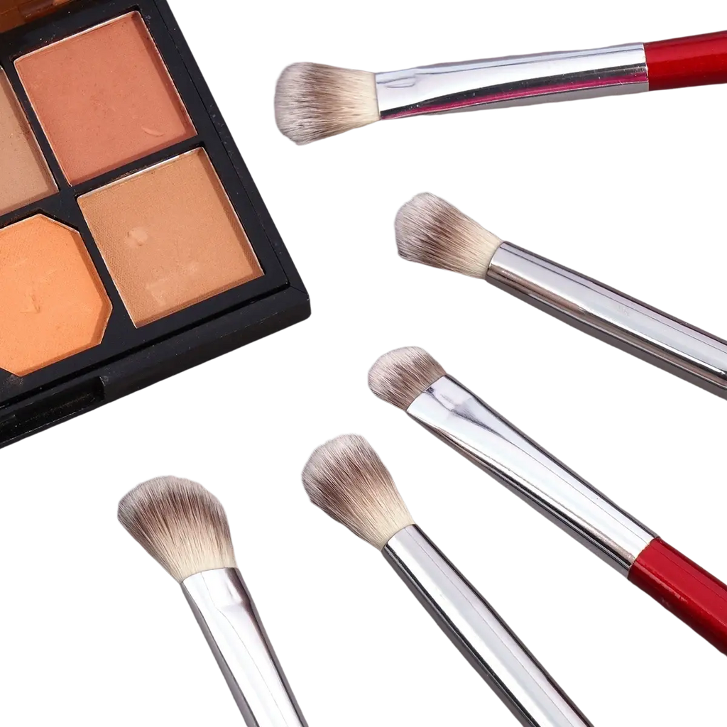 Set of five synthetic hair makeup brushes with red handles silver ferrules and gradient bristles beside eyeshadow palette