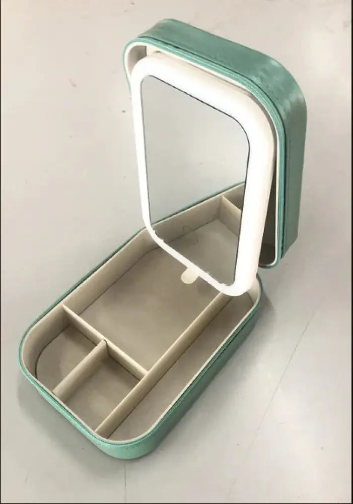 A mint green portable led travel makeup mirror and jewelry storage box with white-trimmed mirror lid and beige interior