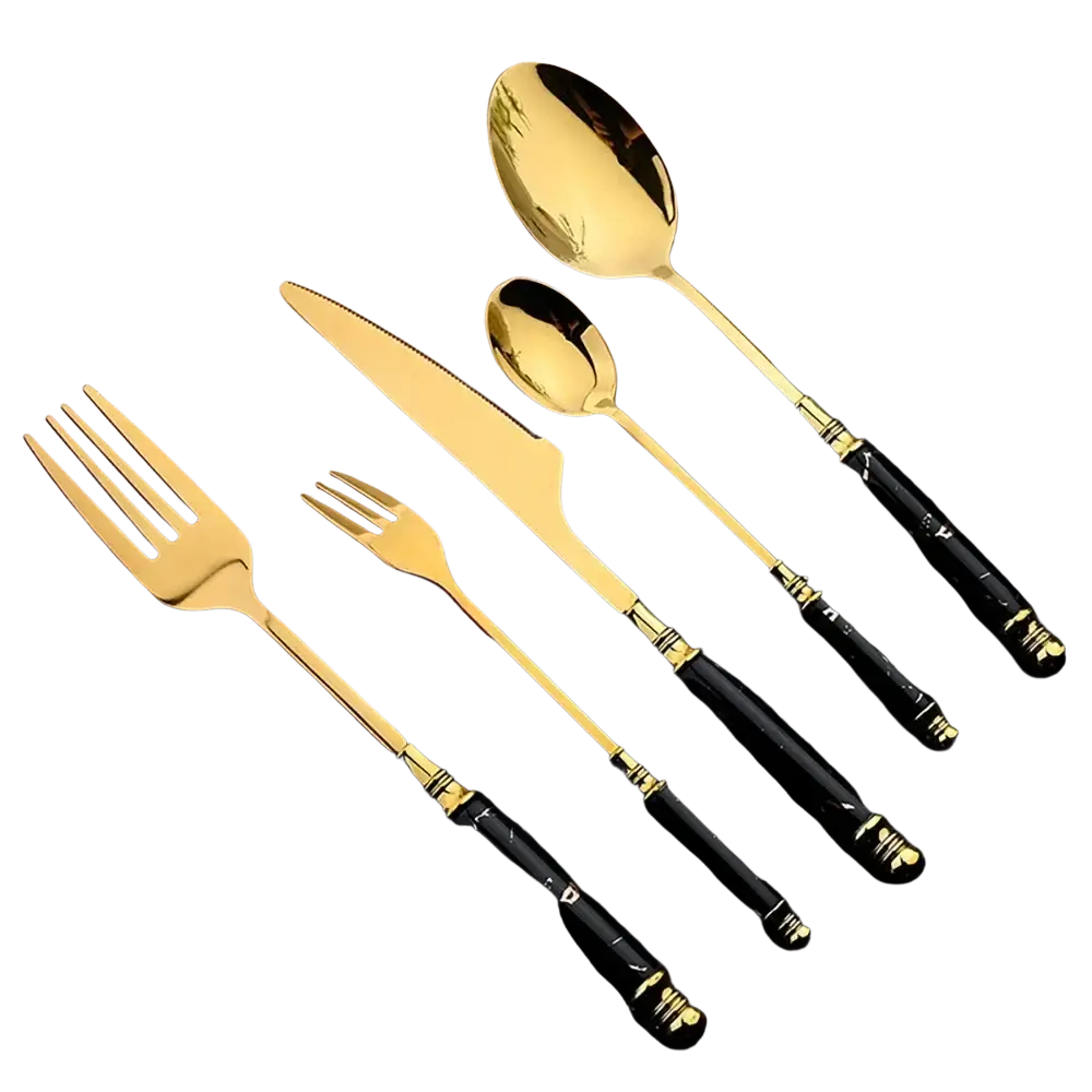 Elegant gold-toned marble handle cutlery set with black marble-patterned handles arranged on a wooden board