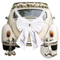 The back side of a cream vintage Volkswagen Beetle features a large white satin just married car bow wedding decoration