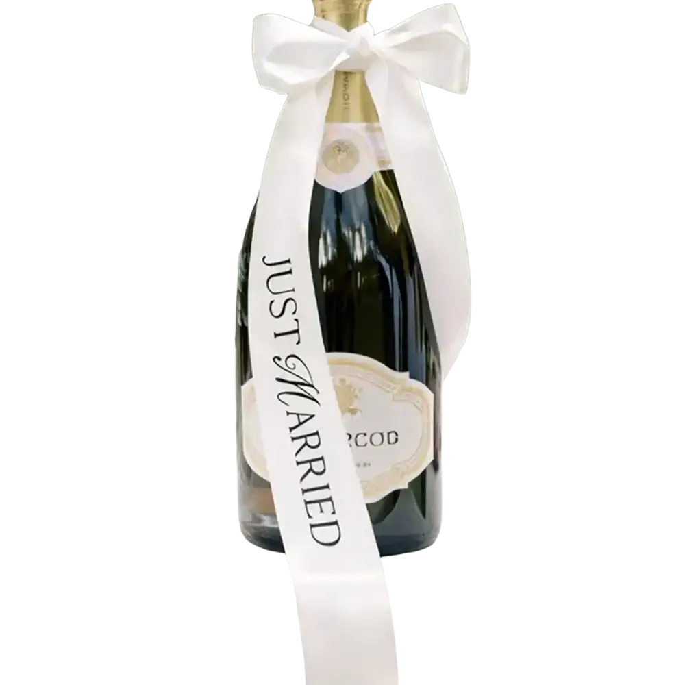 A dark green glass sparkling wine bottle with a white satin just married ribbon for wedding decor