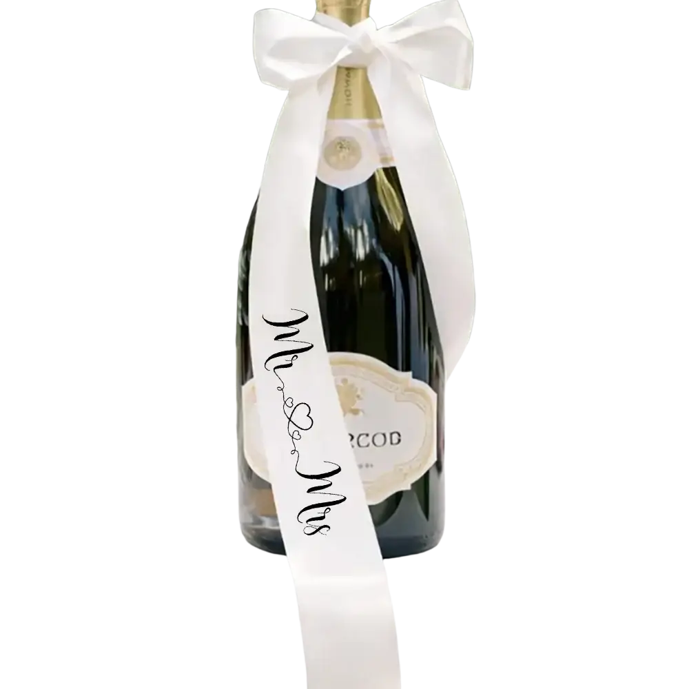 A dark green glass champagne bottle with a white satin ribbon and black cursive mr & mrs script wedding decor