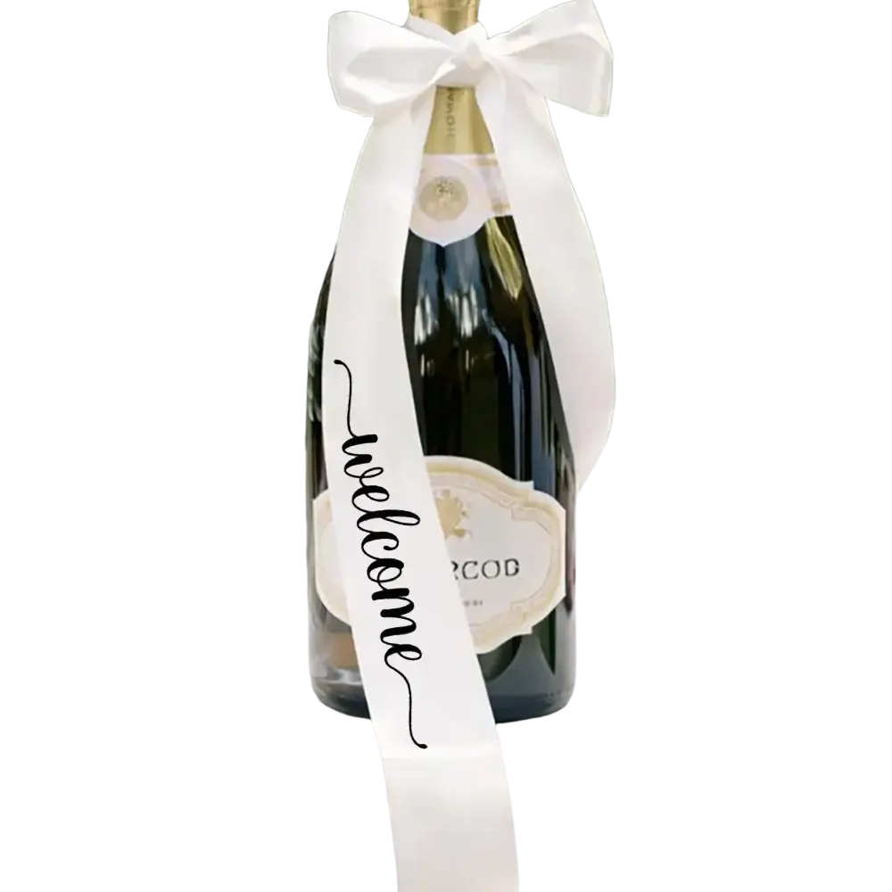 A dark green glass just married wine bottle decorated with a white satin welcome ribbon bow for wedding decor