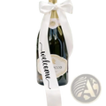 A dark green glass just married wine bottle decorated with a white satin welcome ribbon bow for wedding decor