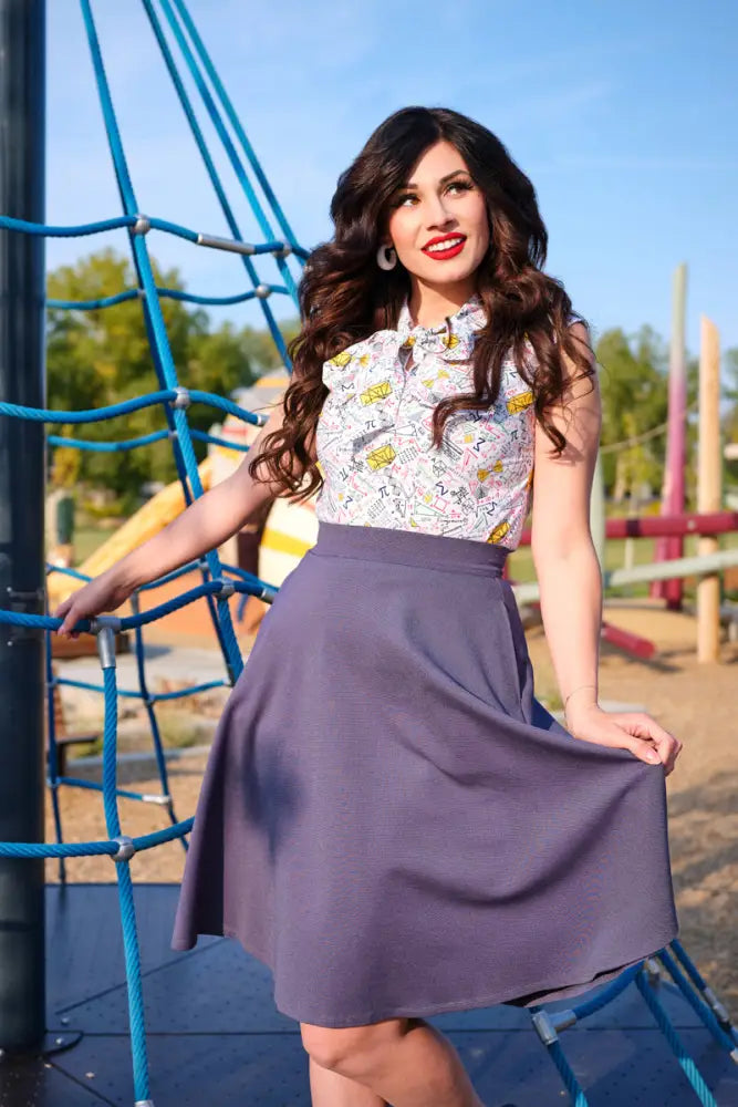 A woman wearing a plus size math print bow neck cotton blouse with sleeveless cartoon print and a purple skirt