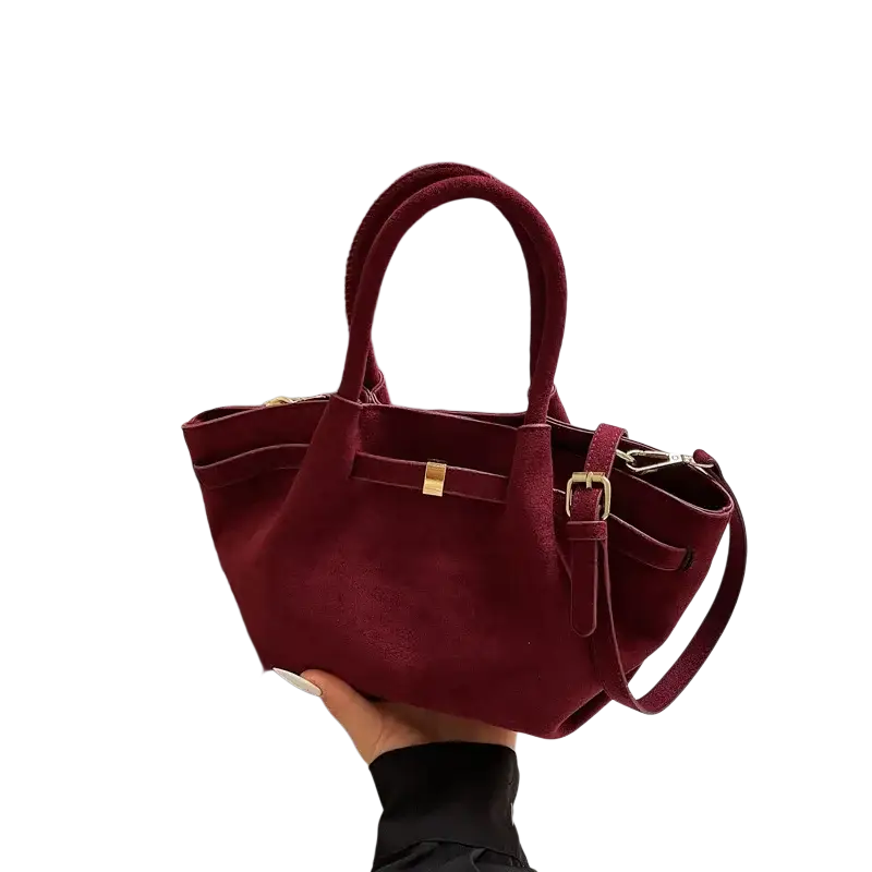 A burgundy suede tote bag with gold-tone hardware and detachable shoulder strap for versatile crossbody use