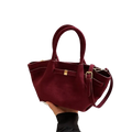 A burgundy suede tote bag with gold-tone hardware and detachable shoulder strap for versatile crossbody use