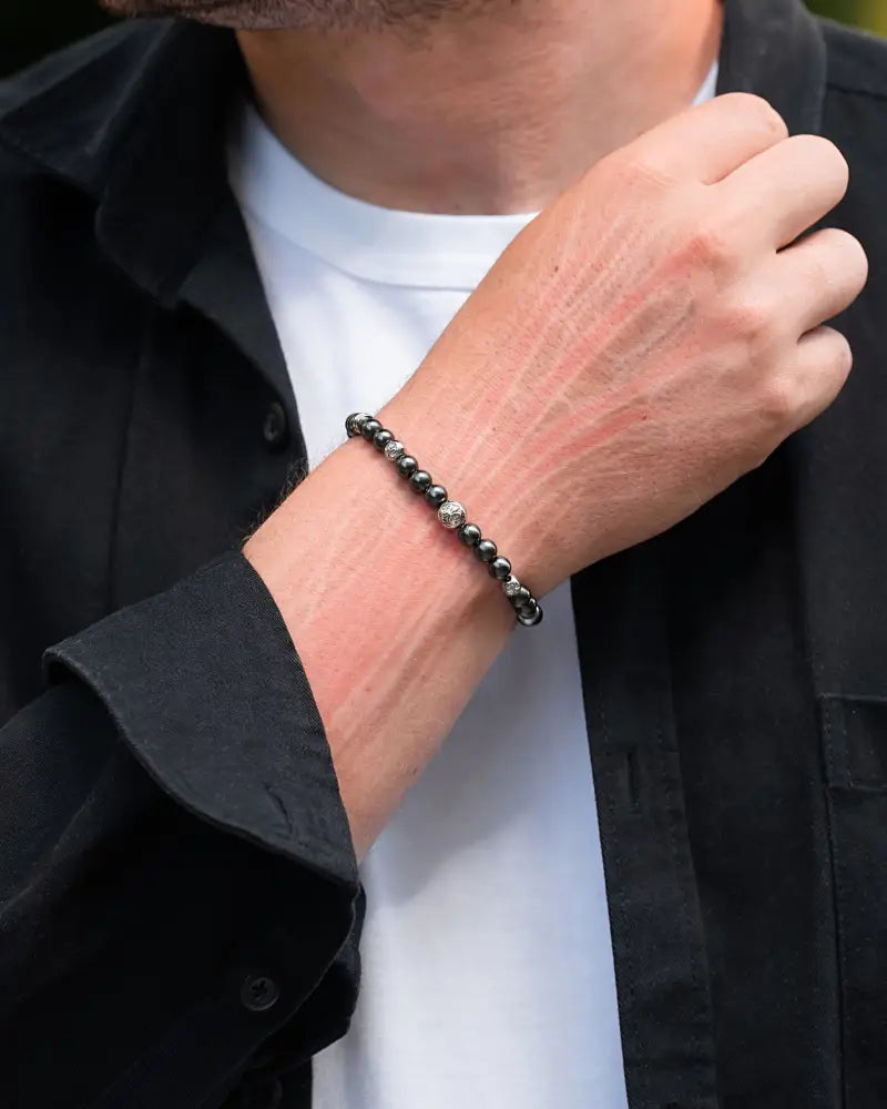 A black beaded magnetic hematite bracelet featuring a silver-toned skull charm for strength and style