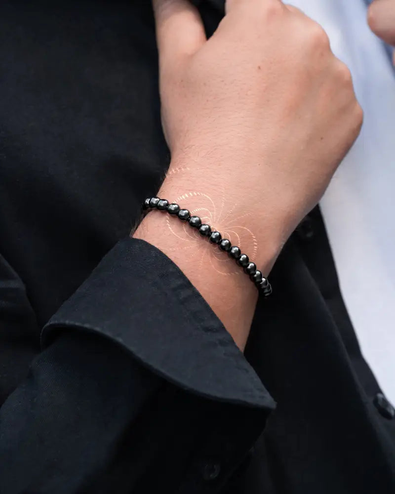 Black beaded max strength magnetic hematite bracelet with stainless steel clasp worn on wrist showing front view