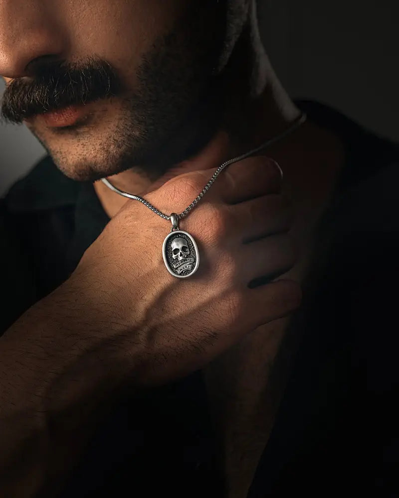 Silver stainless steel memento mori skull pendant with oval frame hanging from a fine chain necklace