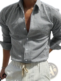 A man wearing a black and white vertically striped long sleeve casual button down shirt with rolled sleeves