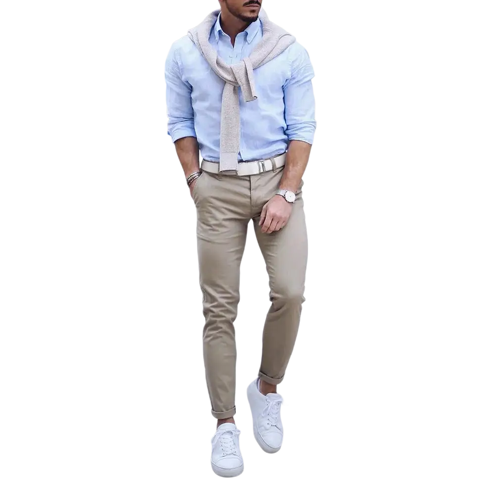 Un homme portant une chemise boutonnée bleu clair, un pantalon chino beige à revers retroussés et des baskets blanches, mettant en valeur une ceinture à cliquet en cuir pour homme avec une boucle automatique.