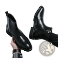 Men’s black patent leather chelsea boots with glossy finish and brogue detailing on the pointed toe