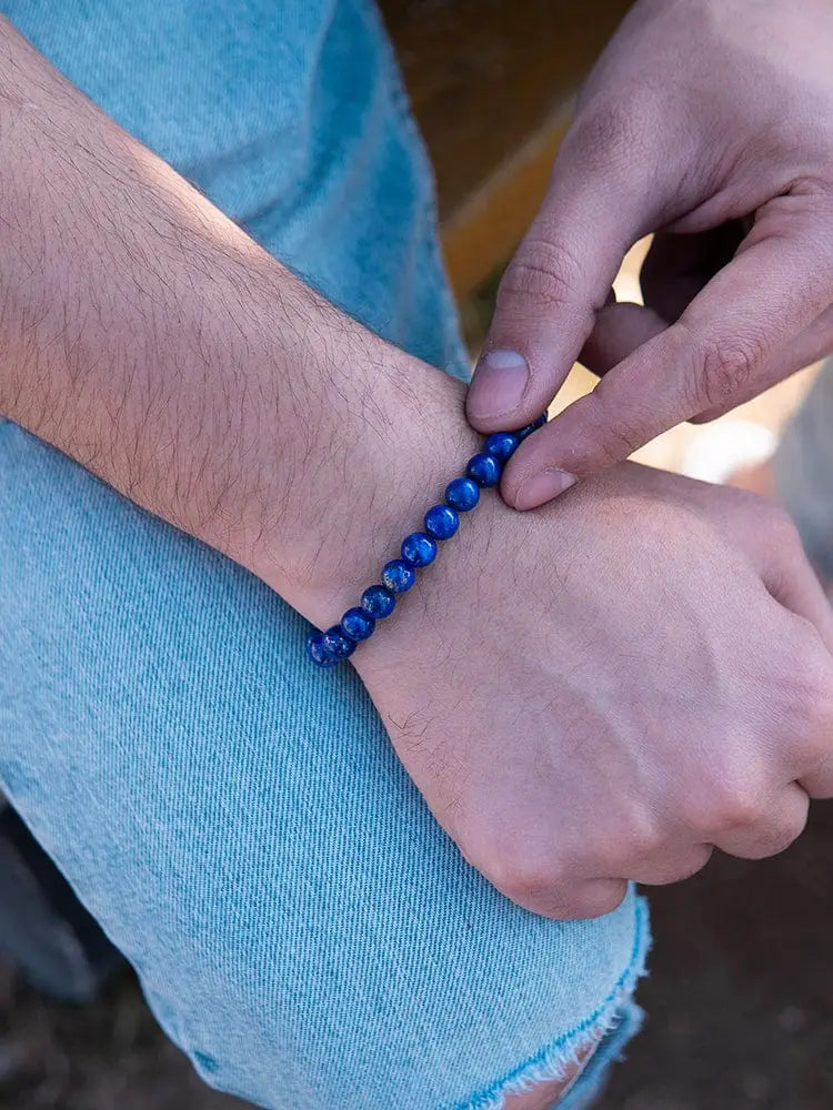Men’s blue lapis lazuli beaded bracelet with silver clasp worn on wrist showcasing vibrant blue stones