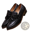 Black leather tassel loafers with a polished finish and contrasting tan soles.