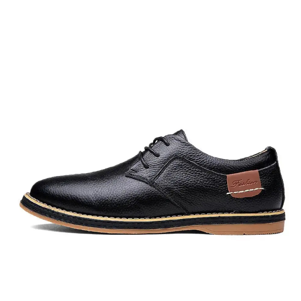 Men’s British leather lace-up dress shoe in black with textured surface and tan stitching along sole and heel tab