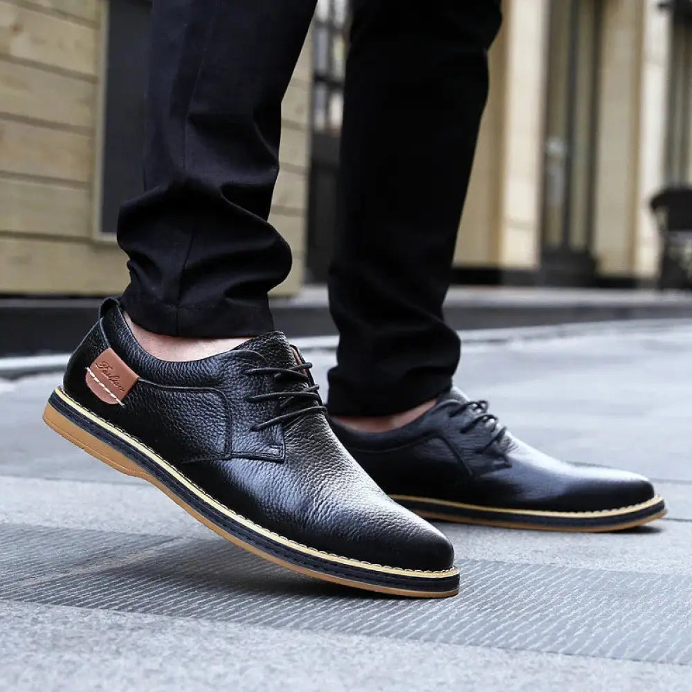 Men’s British leather lace-up dress shoes in black with tan stitching and a brown suede brand patch on the side