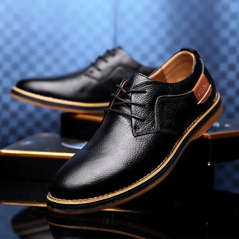 Men’s British leather lace-up dress shoes in black with textured surface and tan stitching along sole and heel tab
