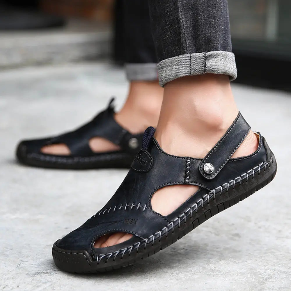 Men’s brown woven leather closed toe beach sandals with black leather straps and adjustable ankle closure featuring stitching
