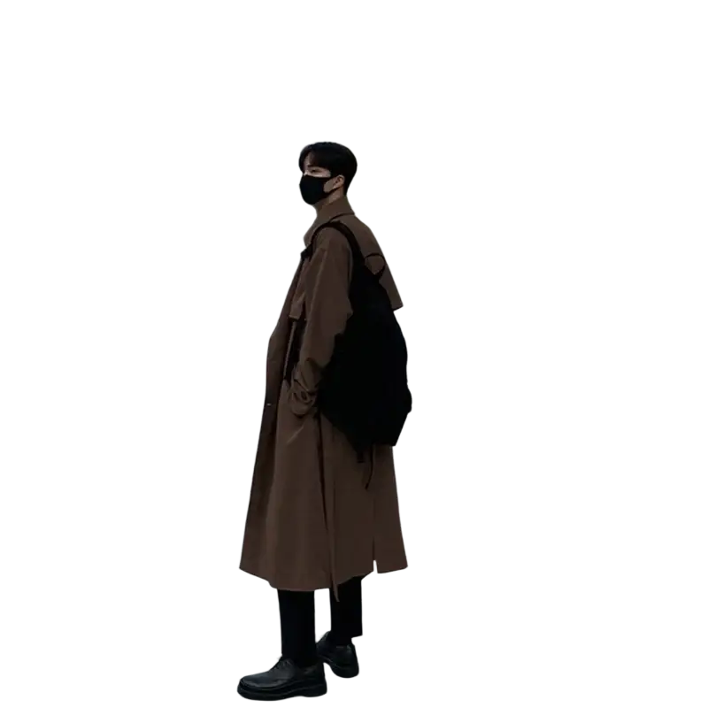 Men’s brown double breasted long trench coat with classic design and subtle texture worn over black pants and shoes