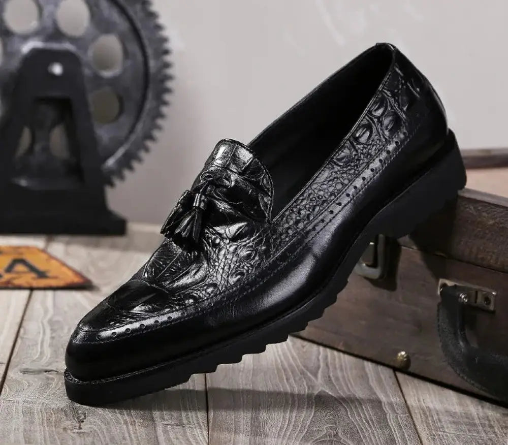 Black crocodile embossed leather men’s loafers with tassel detail and brogue perforations for formal wear