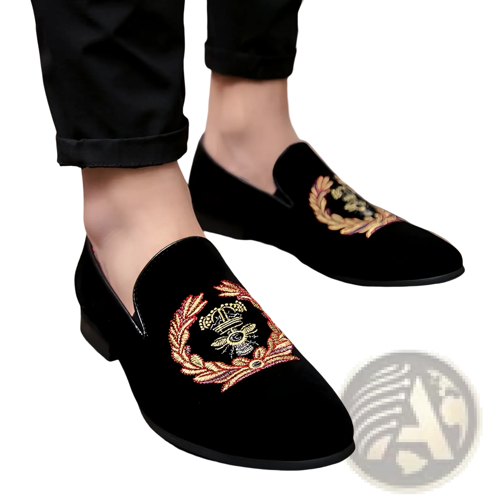 Men’s black velvet loafers with intricate gold and red embroidered laurel wreath and central crown design