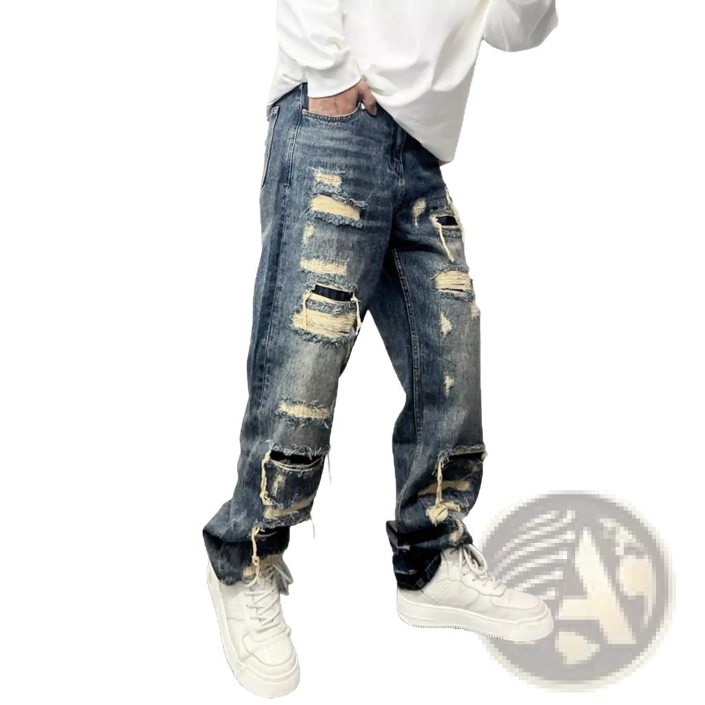 Men’s light blue distressed ripped patch denim jeans featuring multiple frayed and torn areas along the legs