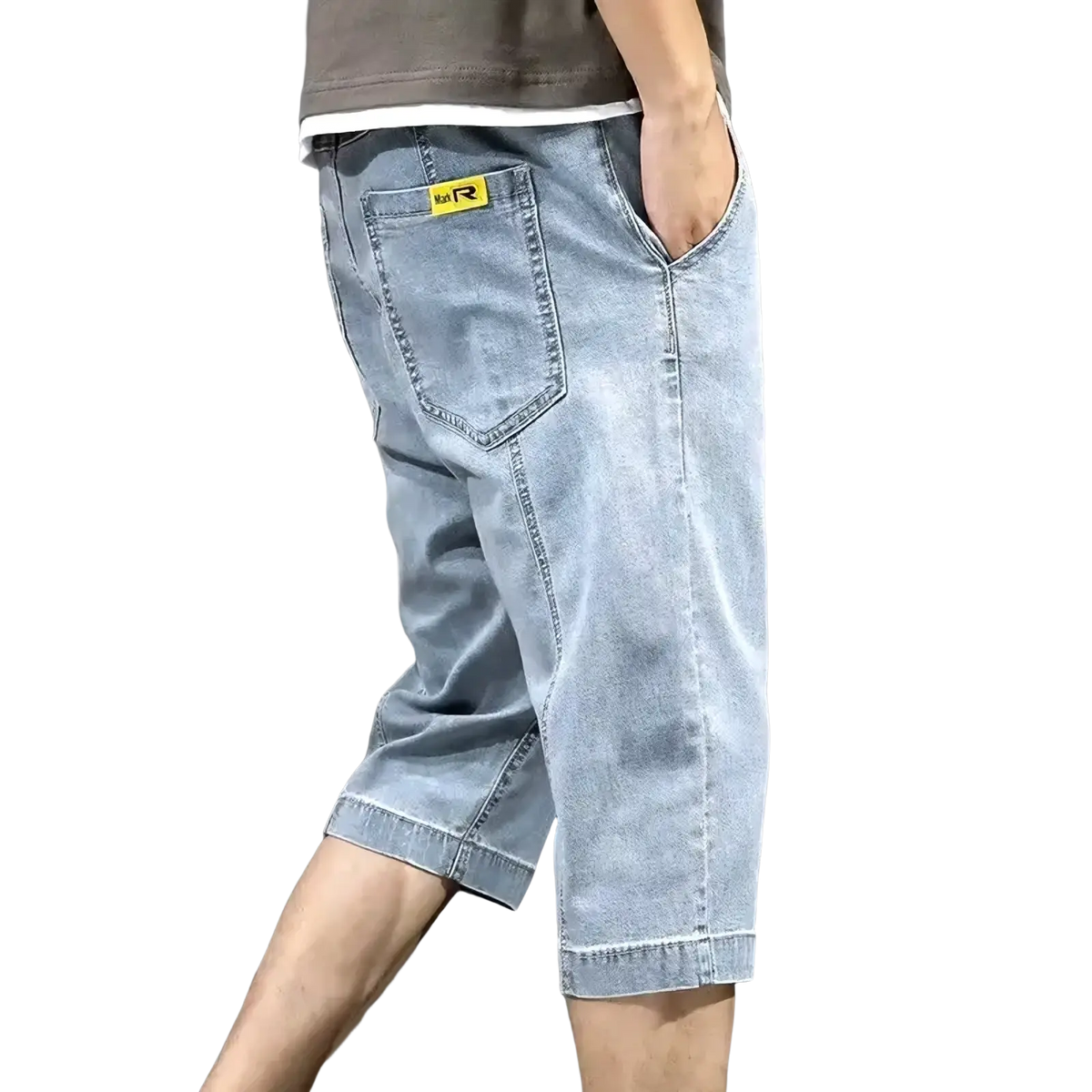 Back side of men’s loose light-wash denim shorts with a yellow brand patch on the back pocket for summer casual wear