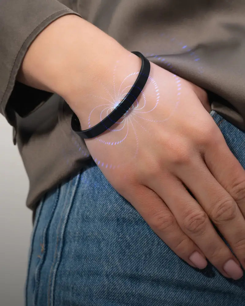 Black men’s brushed magnetic stainless steel cuff bracelet with glowing white light patterns projected on skin