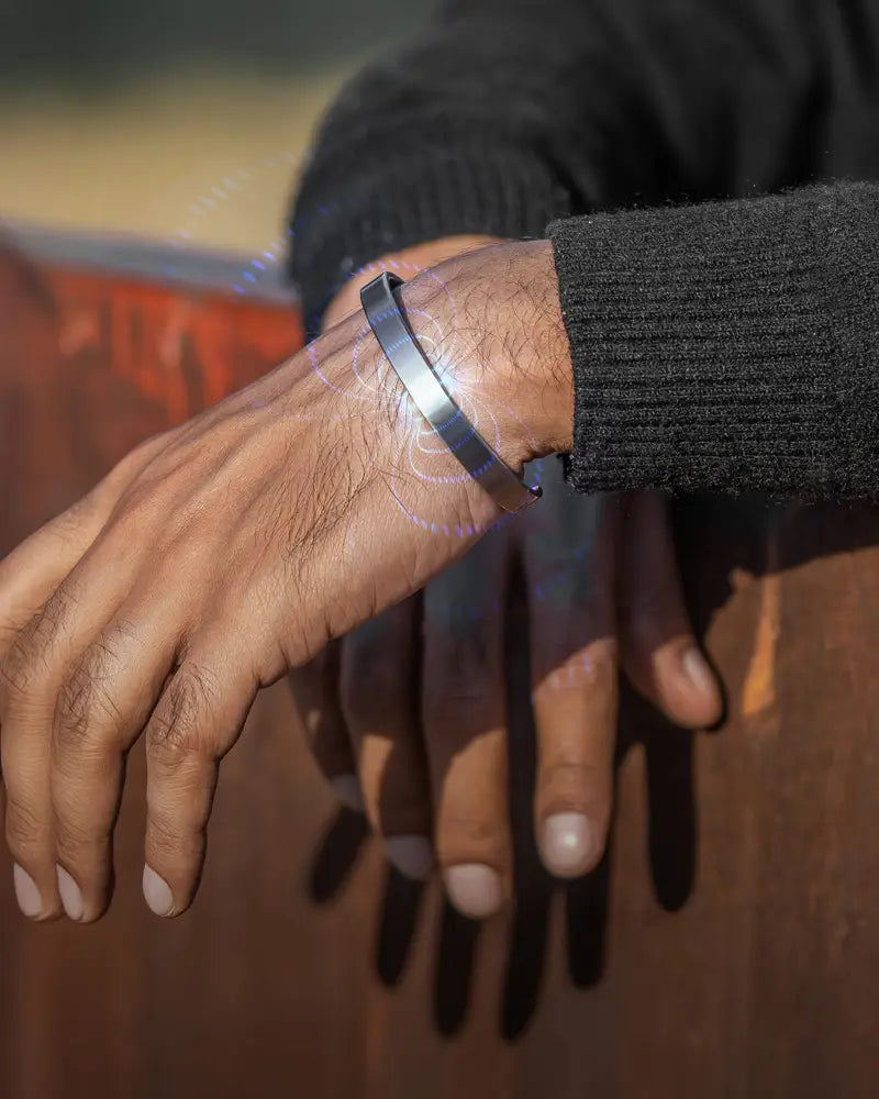 A sleek minimalist men’s brushed silver magnetic therapy cuff bracelet made of metal worn on a wrist