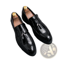 Men’s black patent leather tassel loafers with brogue detailing and gold-toned metallic strap shoe trees