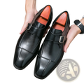 Black leather monk strap shoes with silver buckles and orange insoles.