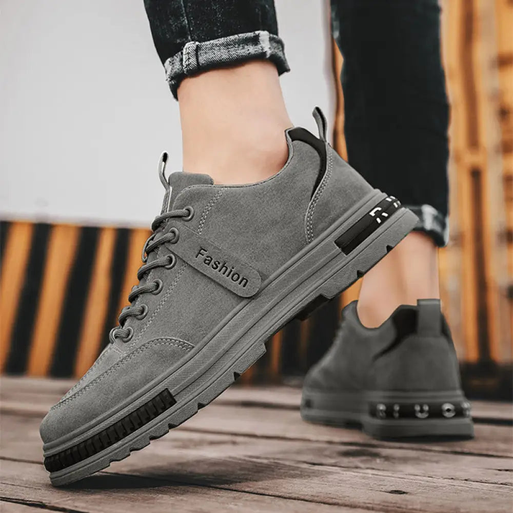 Gray suede low-top luxury men’s rugged platform sneaker with black rubber sole and fashion branding for breathable sport use