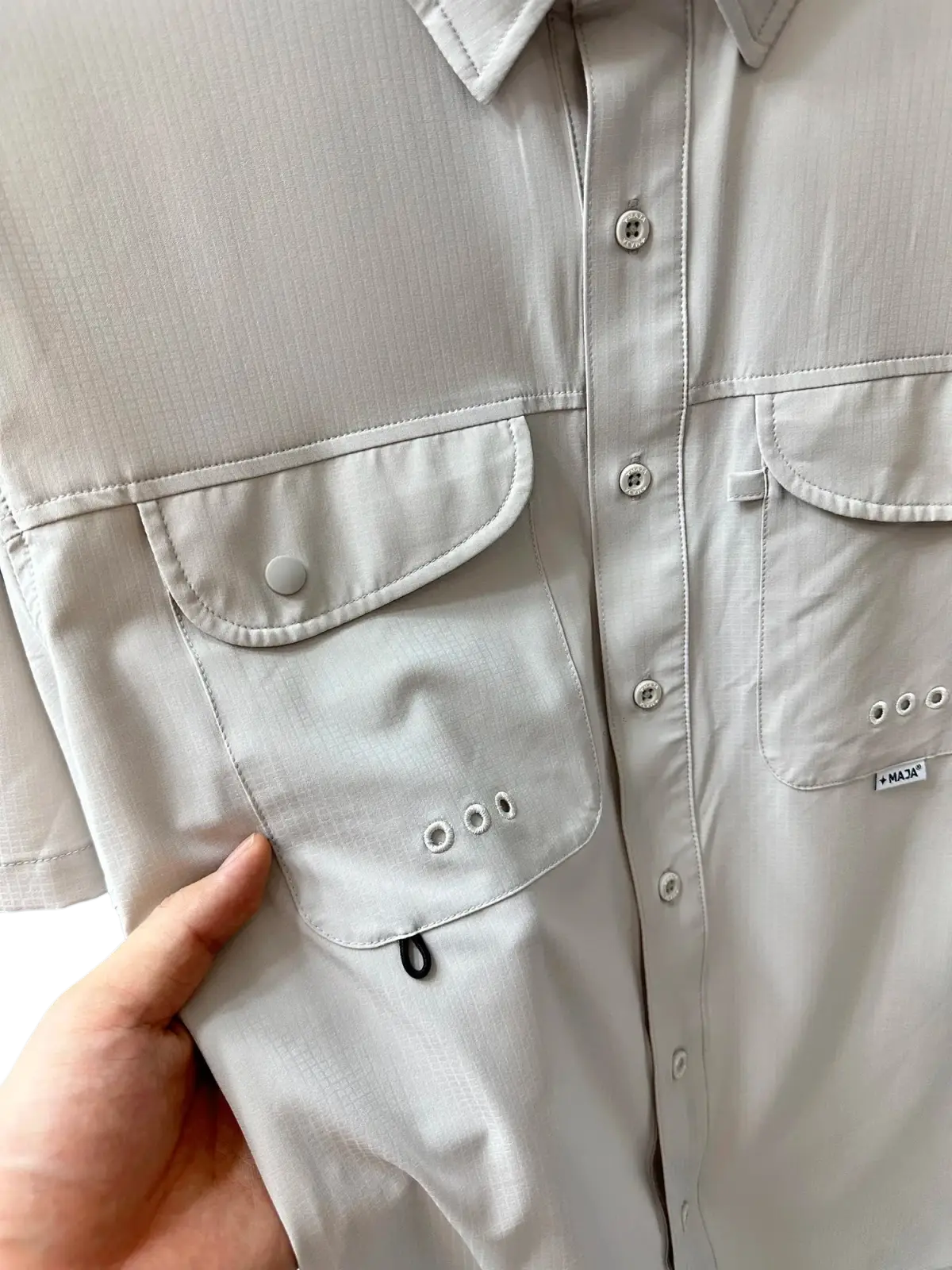 Men’s light gray stretch outdoor shirt made of textured quick dry fabric with buttoned chest pockets and subtle brand tag