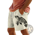 Men’s beige swim trunks featuring a detailed black and gray watercolor-style sea turtle graphic on the front