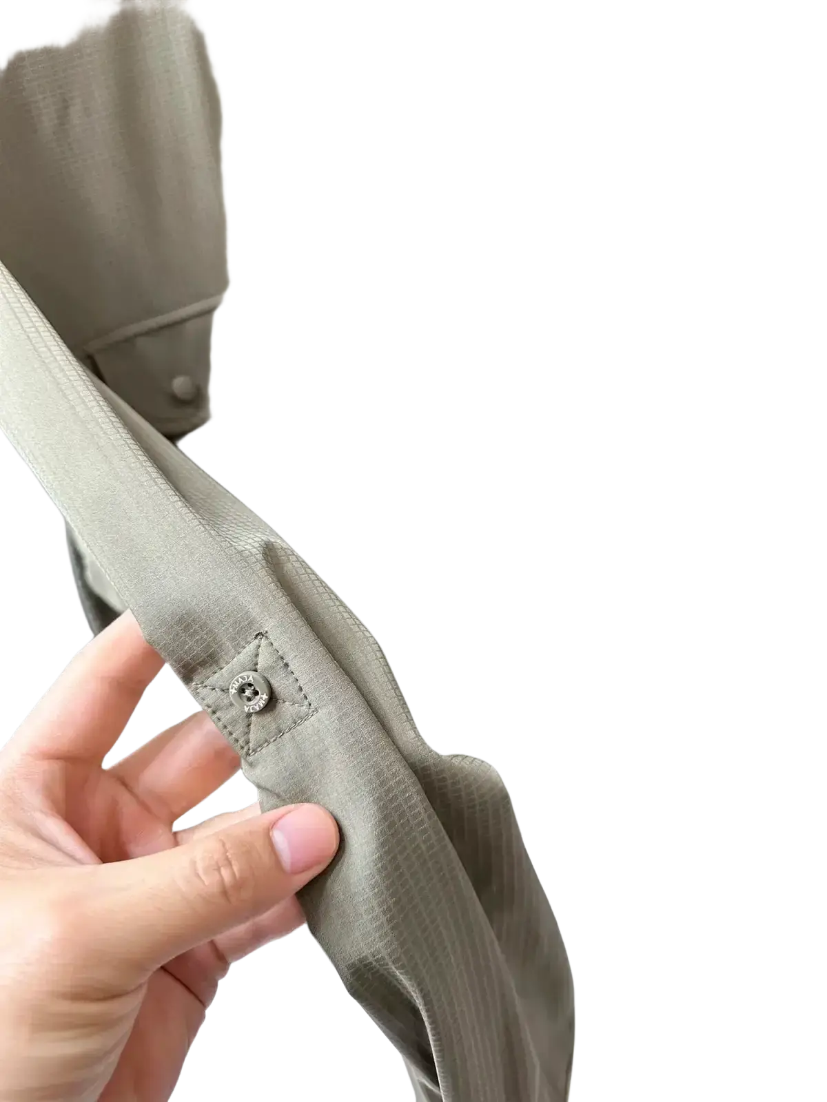 A close-up of a light gray textured fabric sleeve with a metallic button on a men’s tactical outdoor long sleeve shirt
