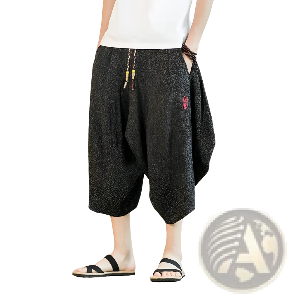 Men’s black textured cotton wide leg lantern harem shorts with drawstring waist and red embroidered patch