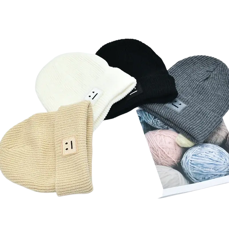 Men’s winter knitted beanie hats in cream black and gray with a smiling face patch on the folded brim