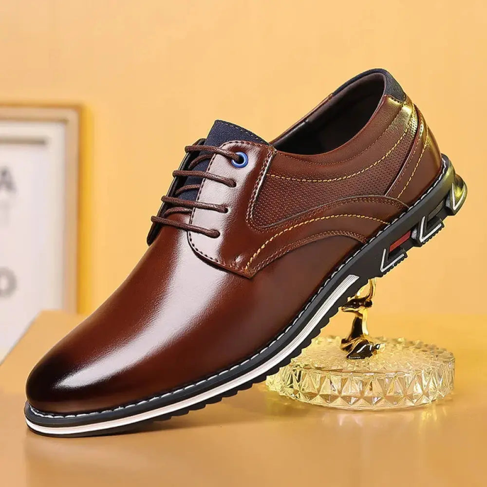 Men’s brown polished leather lace up work shoe with glossy finish, navy blue accents, and black rubber sole with white stitching