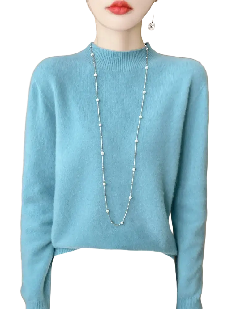 A delicate silver chain necklace with white pearls worn over a light blue merino wool pullover sweater for women