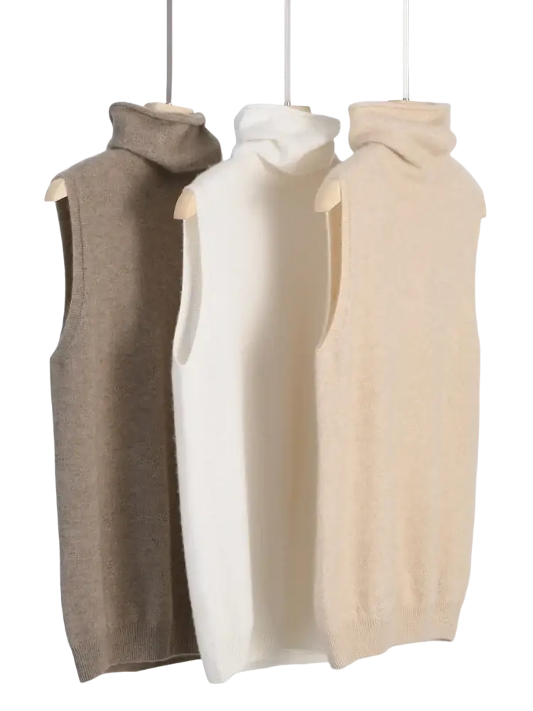 Three sleeveless merino wool turtleneck sweater vests in beige cream and taupe displayed on wooden hangers