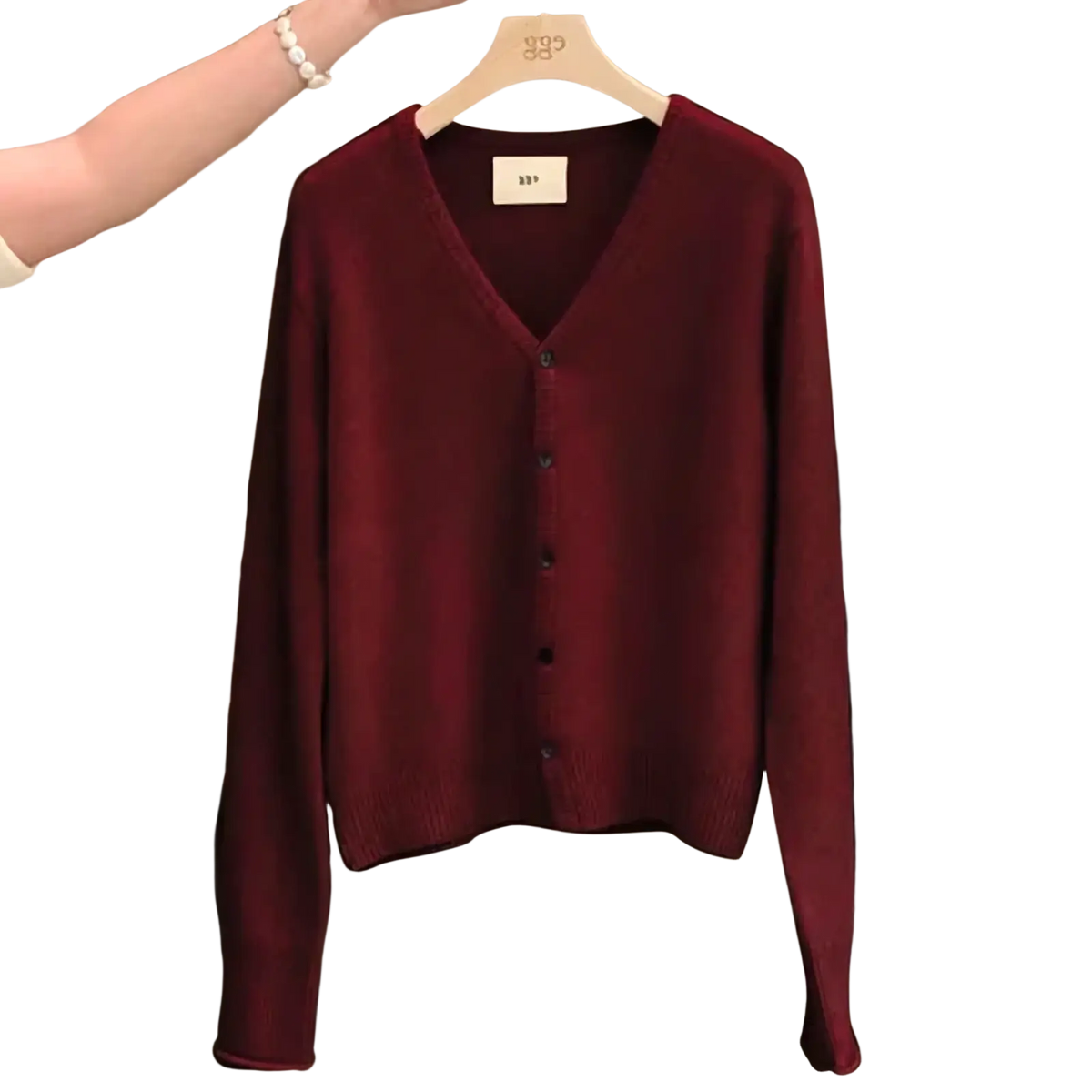 A deep burgundy merino wool v-neck cardigan sweater with long sleeves and black buttons on a wooden hanger