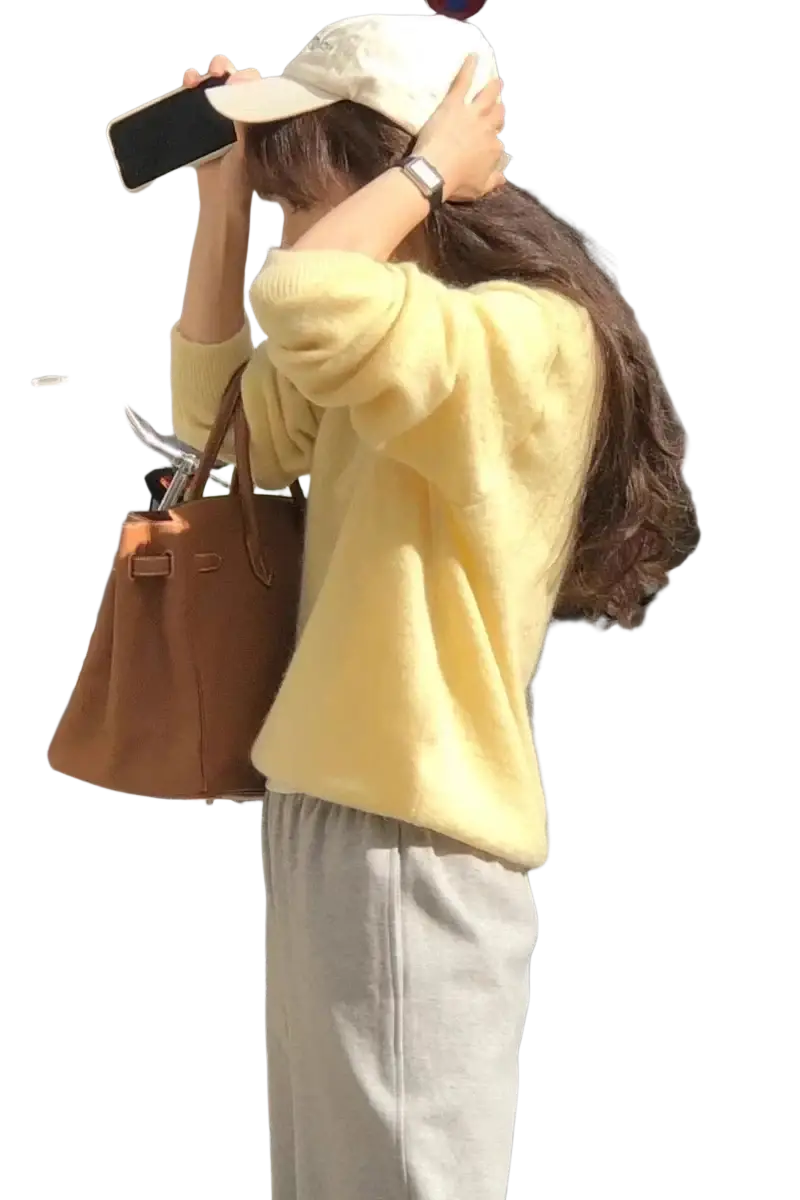 A tan leather handbag with structured design and top handles paired with merino wool v neck women sweater