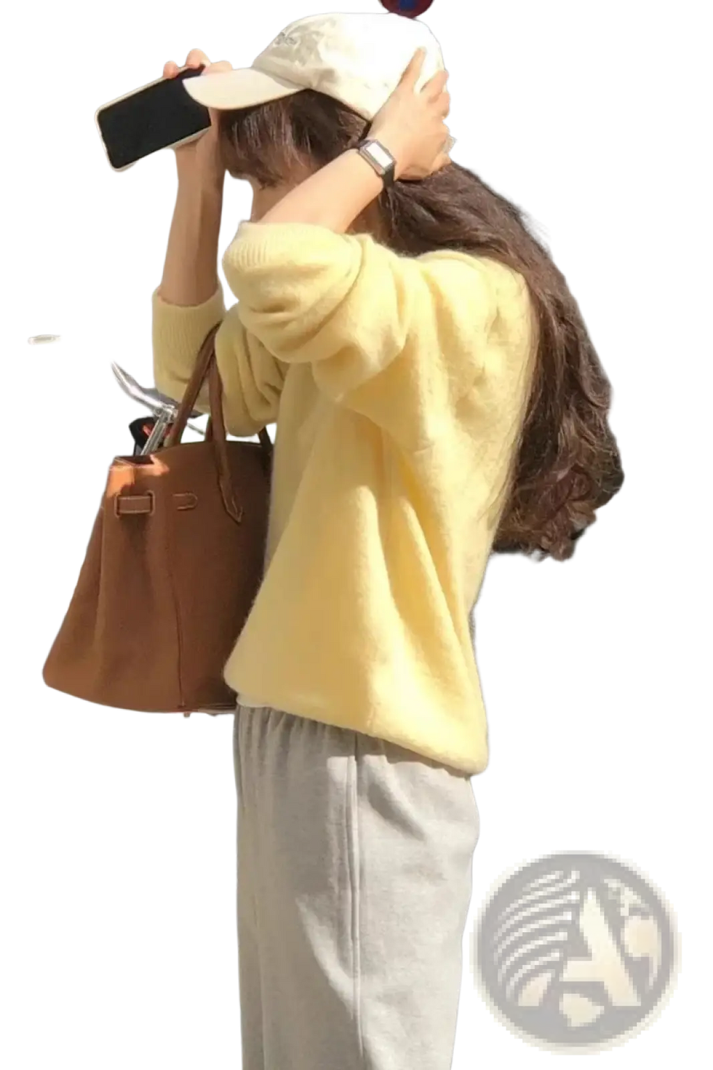 A tan leather handbag with structured design and top handles shown alongside a merino wool v-neck women sweater
