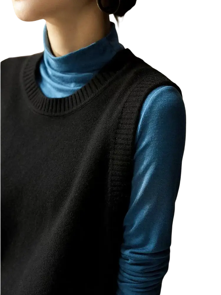 Black knitted sleeveless merino wool women sweater vest worn over a blue turtleneck top for layering warmth
