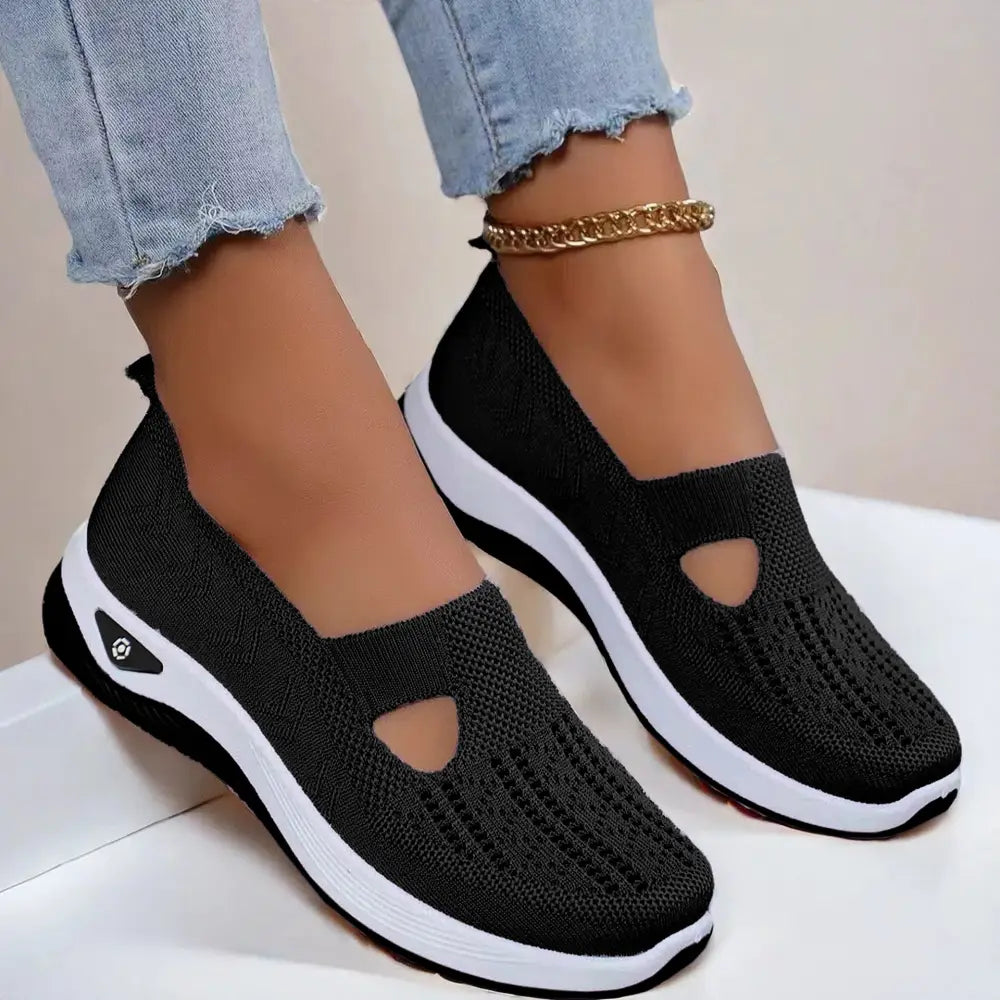 Women’s breathable black knit slip-on sneakers with white rubber sole and decorative toe cutouts for casual wear