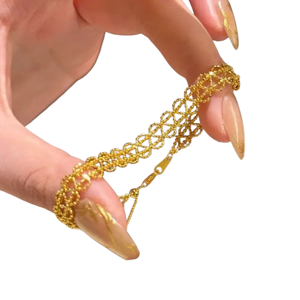 A delicate gold metal lace bracelet with an intricate interlocking circular design and adjustable clasp